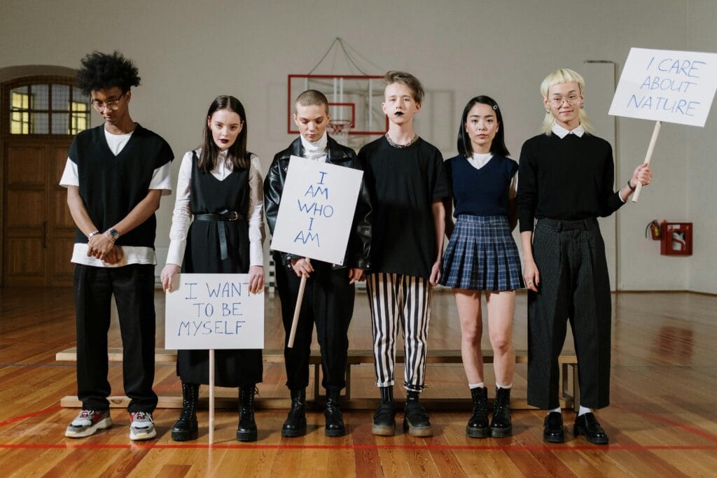 Group of diverse teenagers holding signs expressing individuality in a school gym.