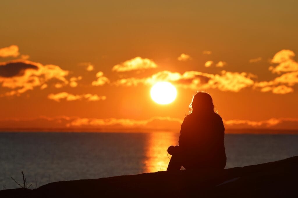 A captivating scene of a person sitting by the sea, observing the life lessons learned from observing natural cycles.