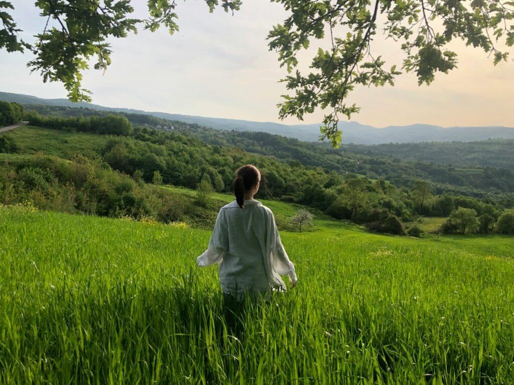 A woman stands in a lush green field,the healing power of nature.