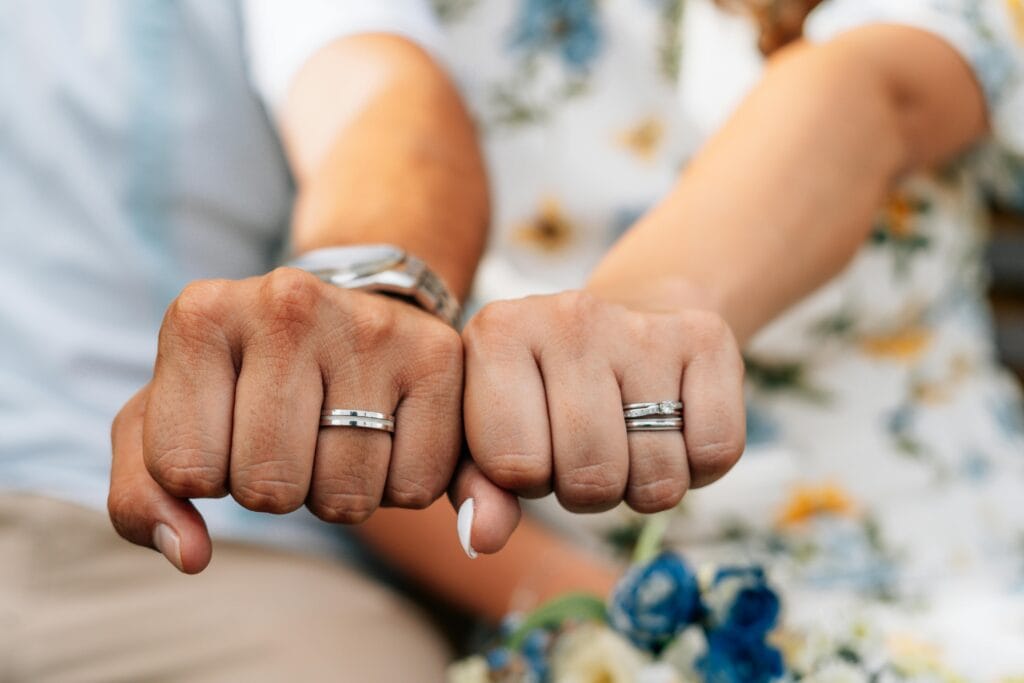 Close-up of a couple showing their wedding rings, emphasizing love and commitment.
