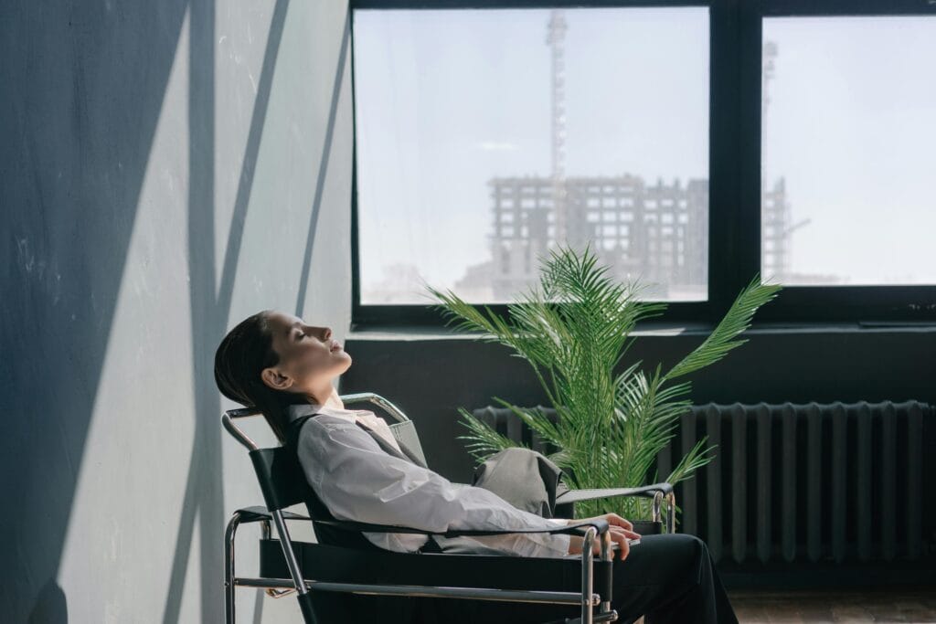 Woman in a minimalist office setting relaxing,this shows that how  to simple mindfulness exercises for busy professionals to stay present.