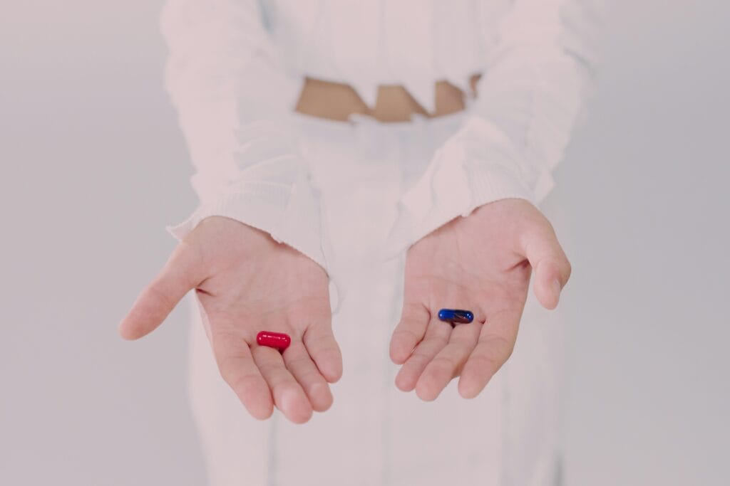 Close-up of hands holding red and blue pills, symbolizing a choice, the battle between ego and altruism in human decision making (inner conflict of choice)