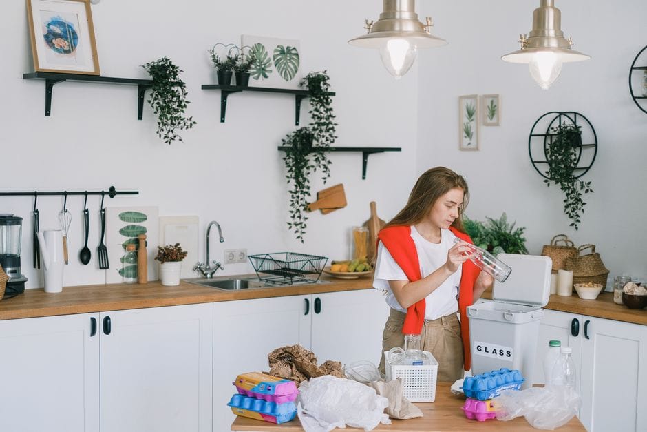 Fresh glass jars and a compost bin in a kitchen showing practical ways to live more sustainably.